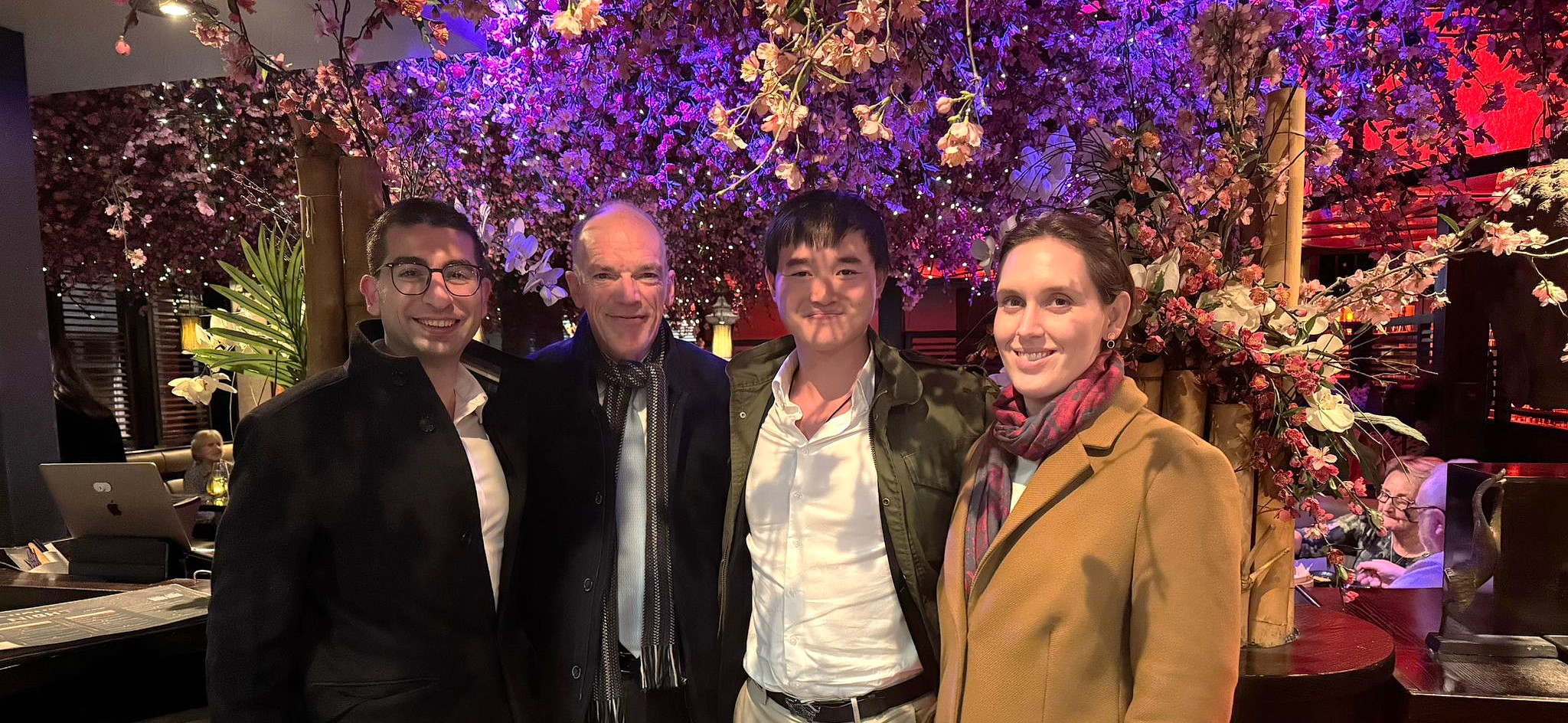 A photo of Can, Volker, Yuk Chi and Elizabeth, underneath a purple tree