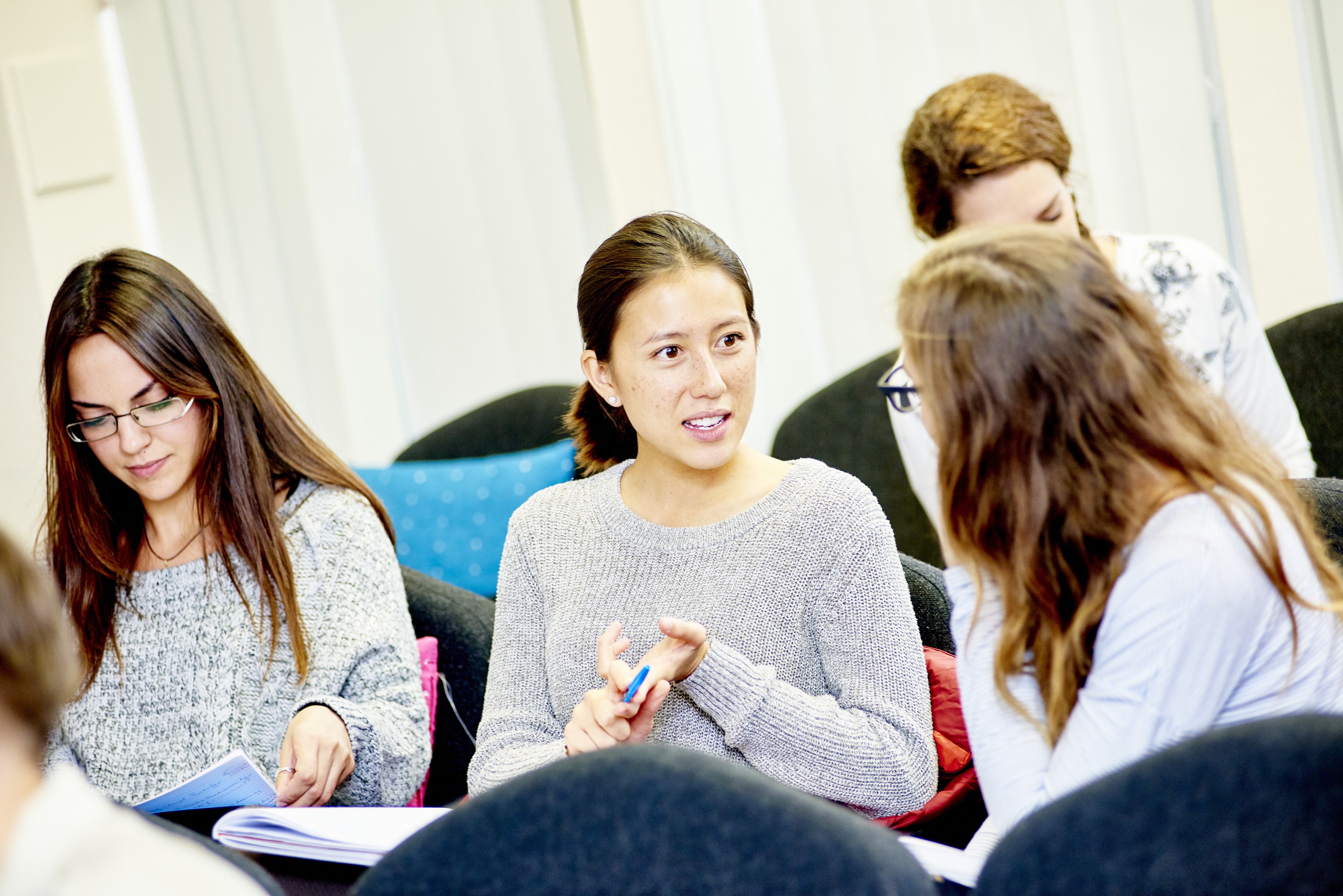 Group of postgraduate students discussing their work in a seminar room