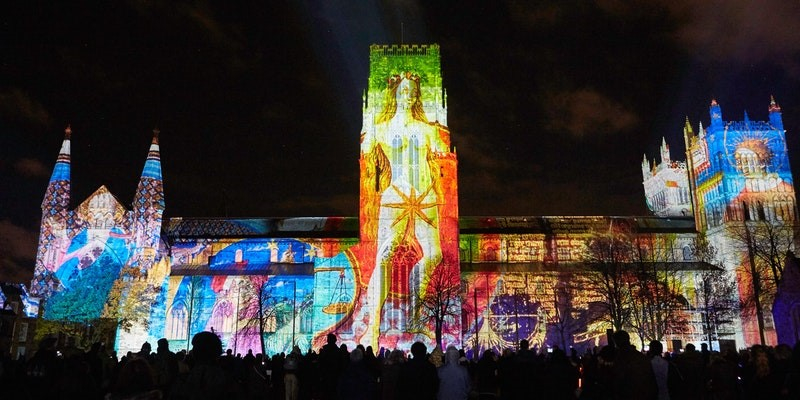 Durham cathedral lit up with colourful lights at night.