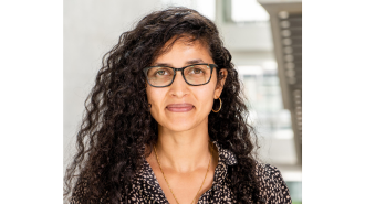 Image of Dr Renu Singh standing in front of a pale background.