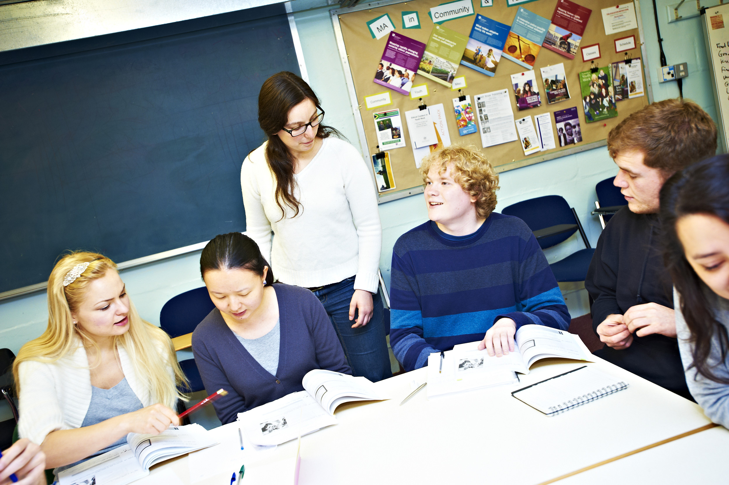 Students reading and discussing a book with their tutor