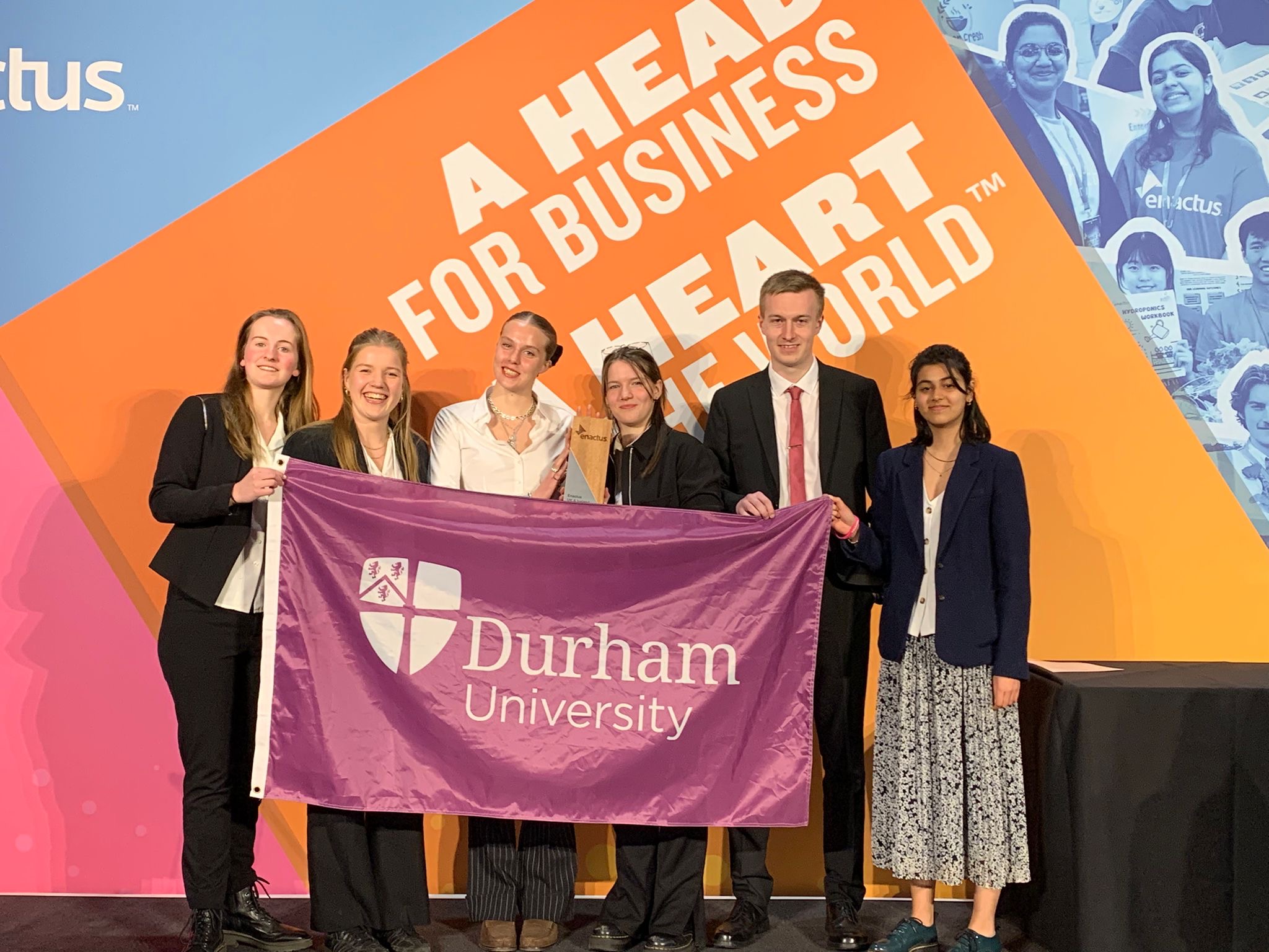 A group of students holding a flag with the Durham University logo