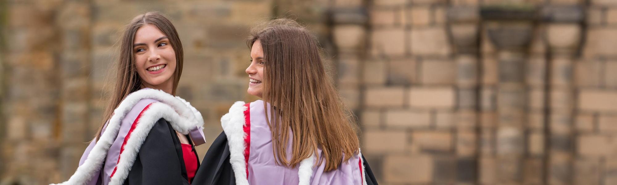 Two graduands in robes outside Durham Cathedral