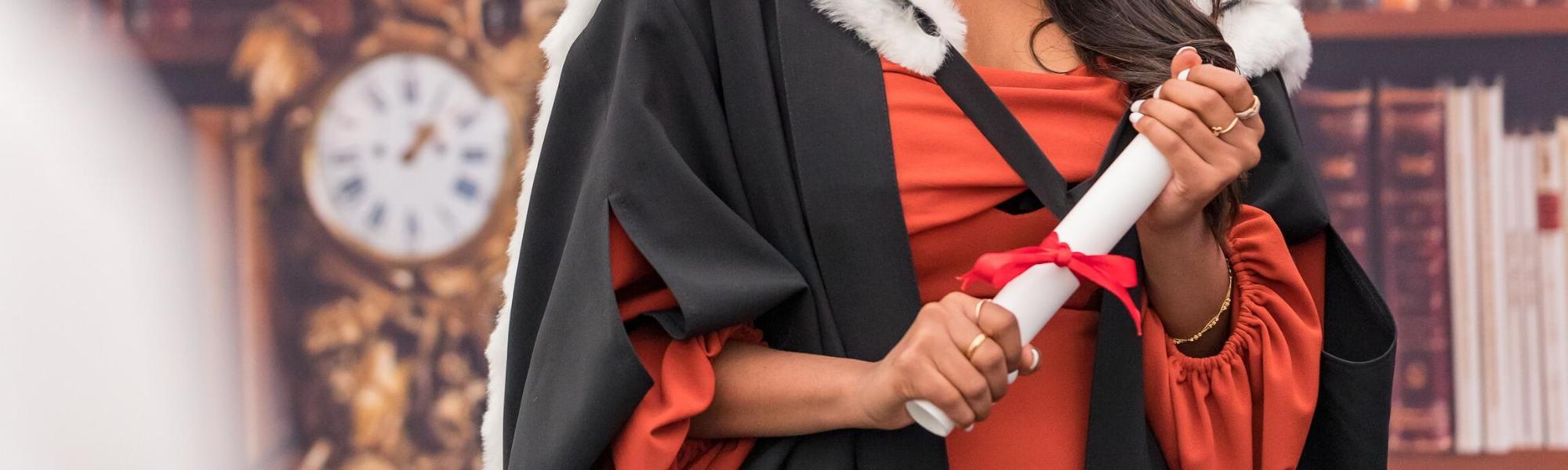 Graduand holding degree parchment for photograph