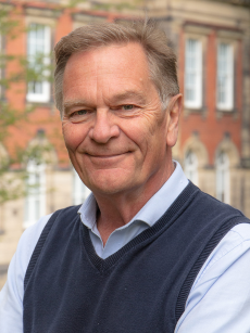 A shot of Ross Forbes smiling in front of an old building.
