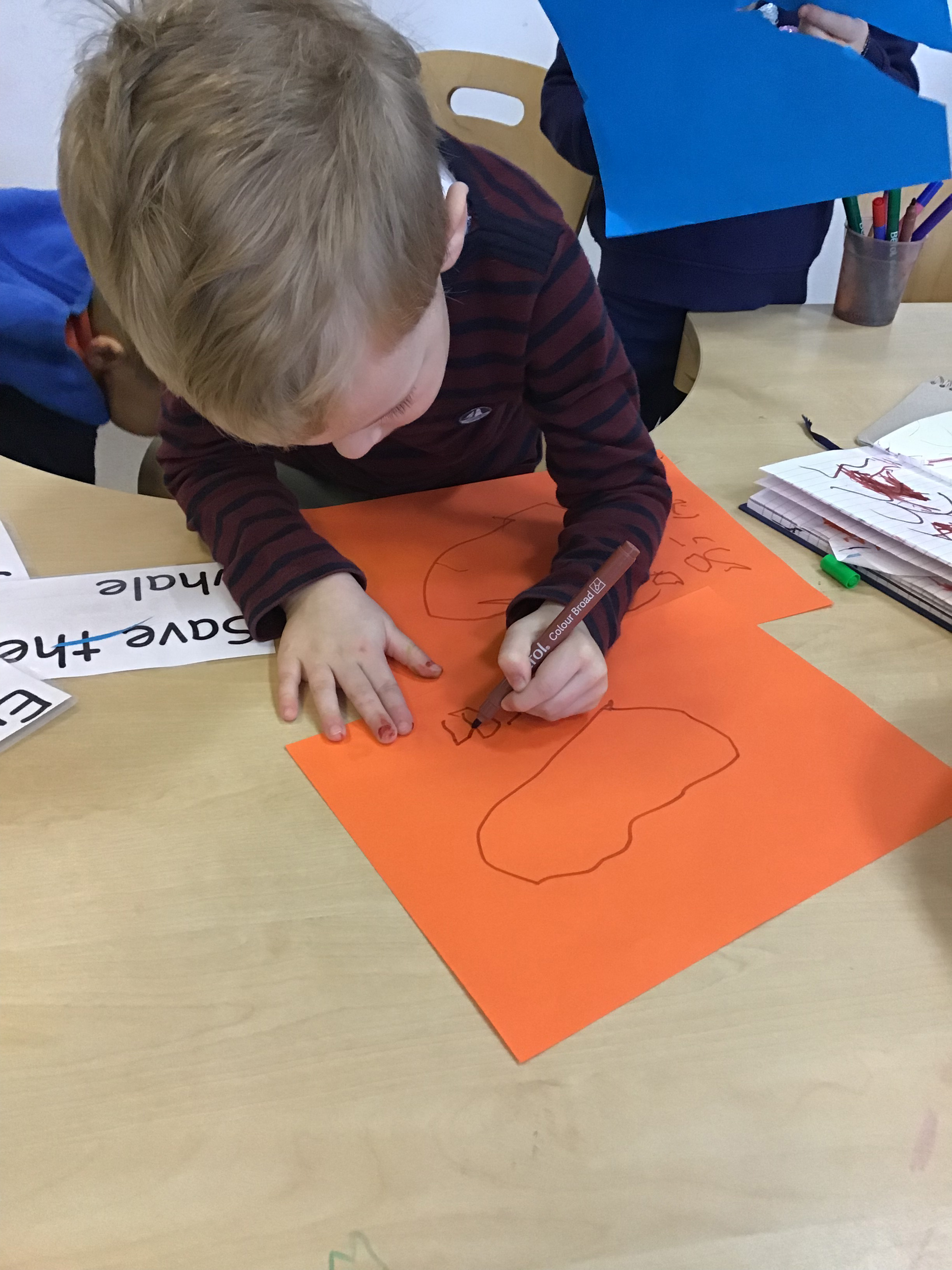 Child drawing on red paper