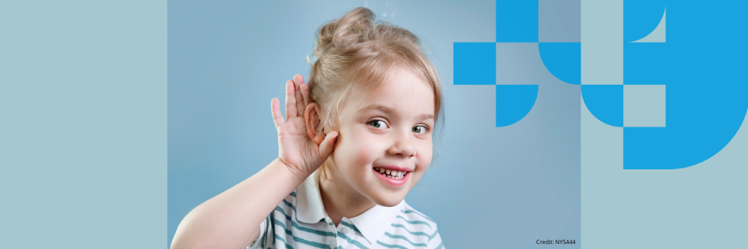 A child smiling and leaning forward with their hand round their ear