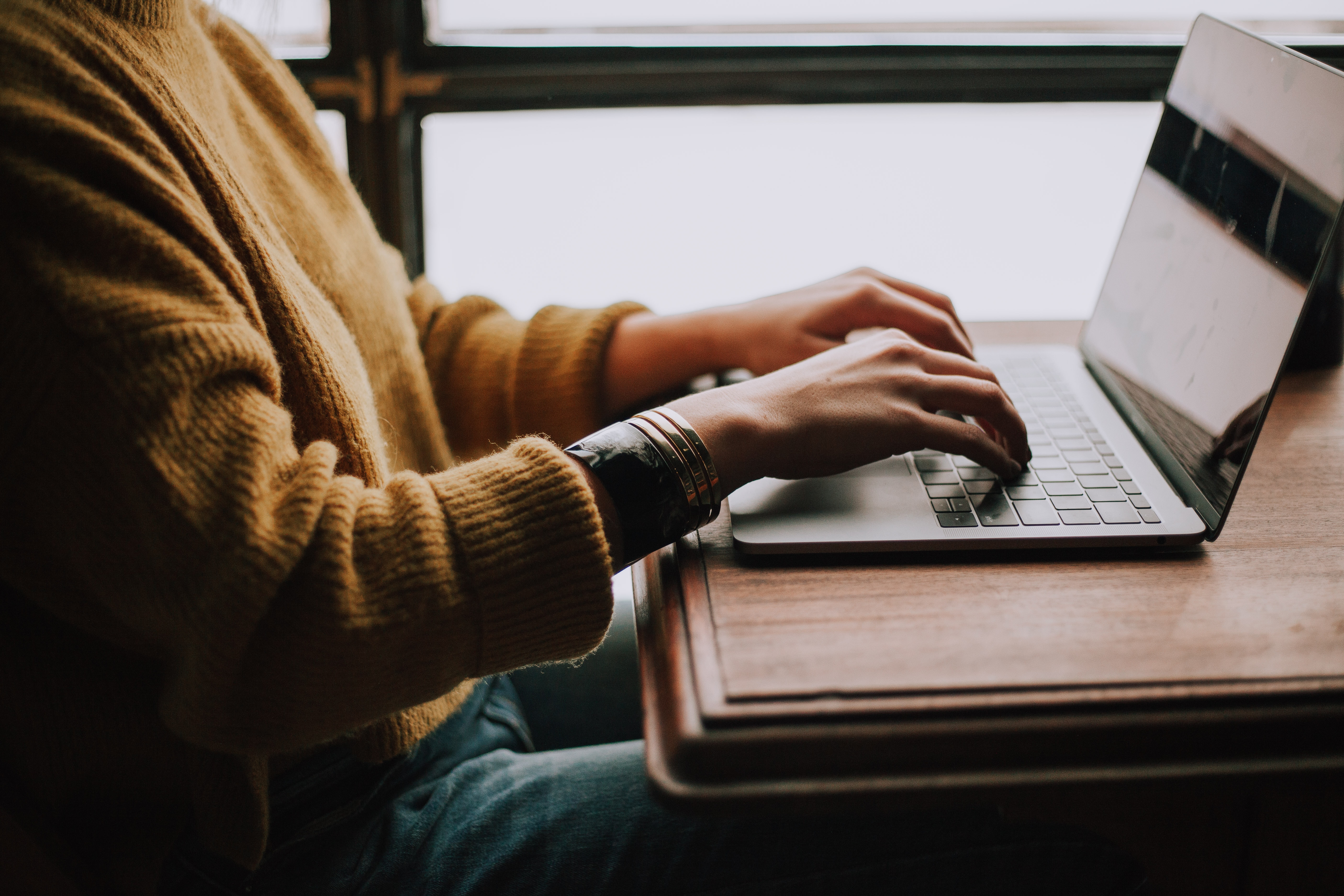 Person sitting at a desk typing on a laptop