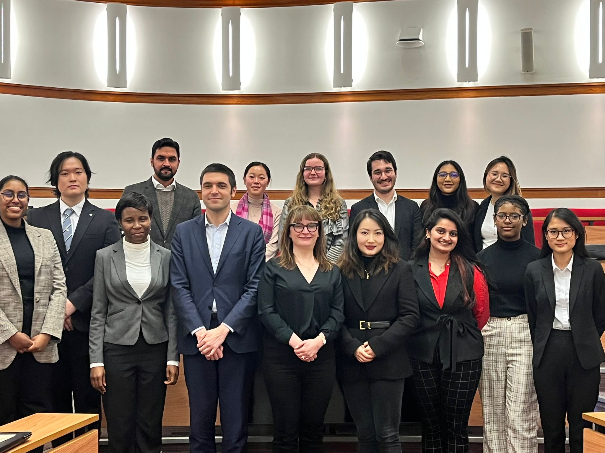 TStaff and Students standing in two rows in a lecture room