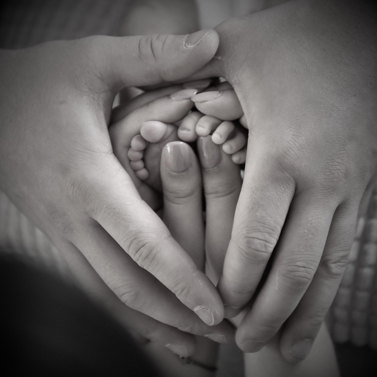 Picture of a mother and father hands holding baby's feet