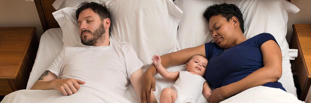 Couple laid in bed with baby