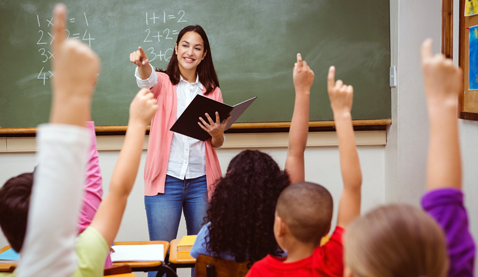 A classroom full of children holding their hands up to answer a question