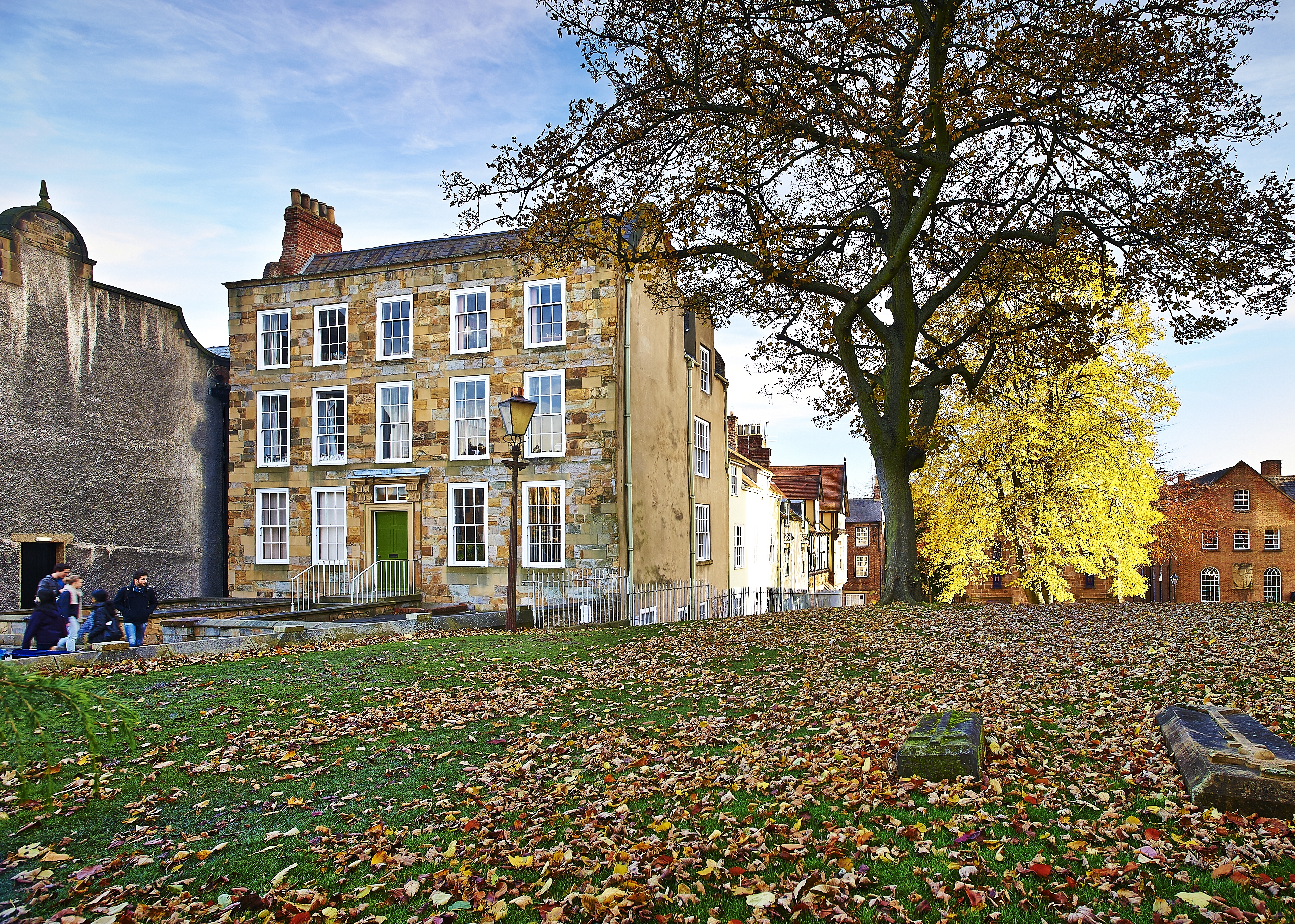 A period building with a tree and autumnal leaves