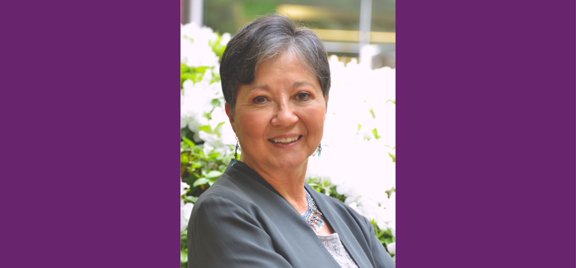 A smiling Asian woman wearing a grey suit