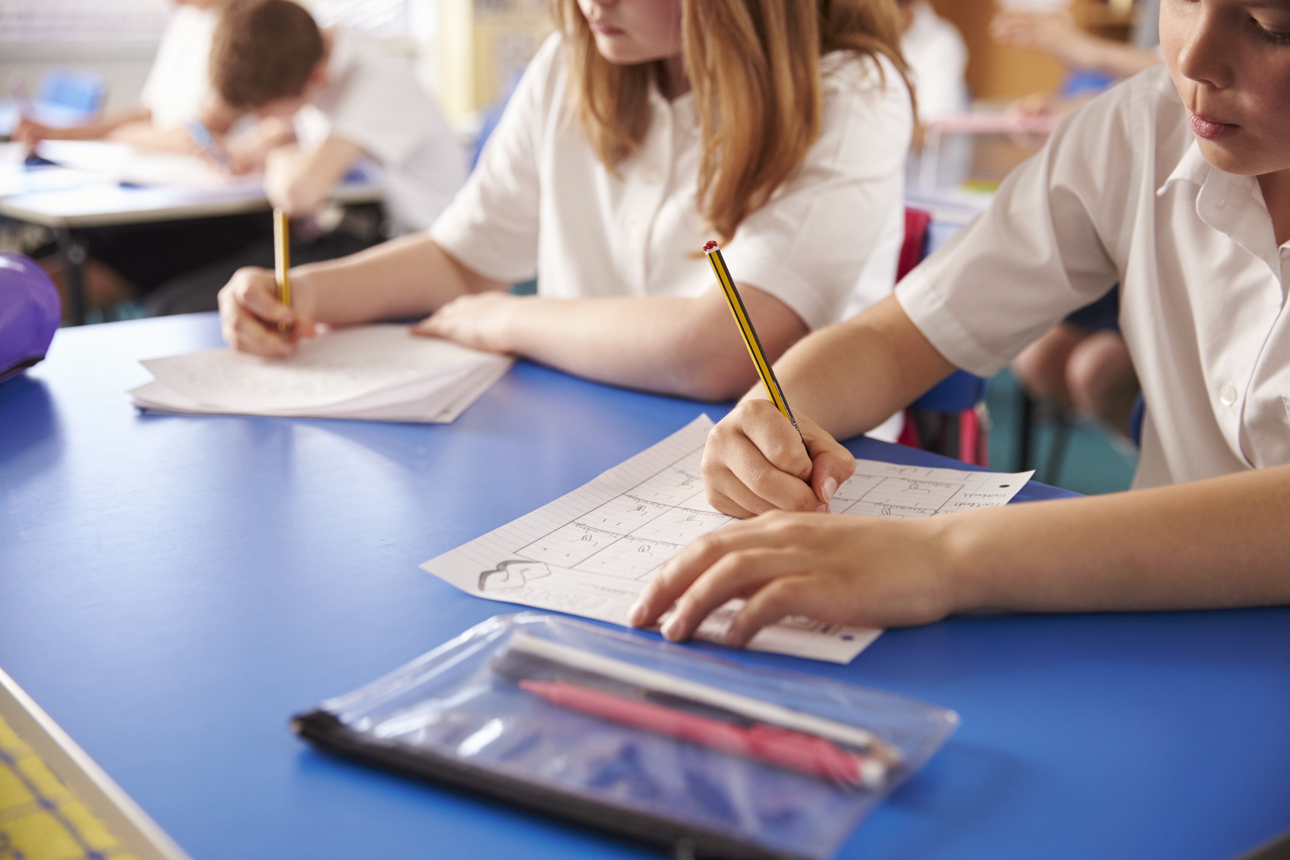 Primary school pupils in class practicing writing.