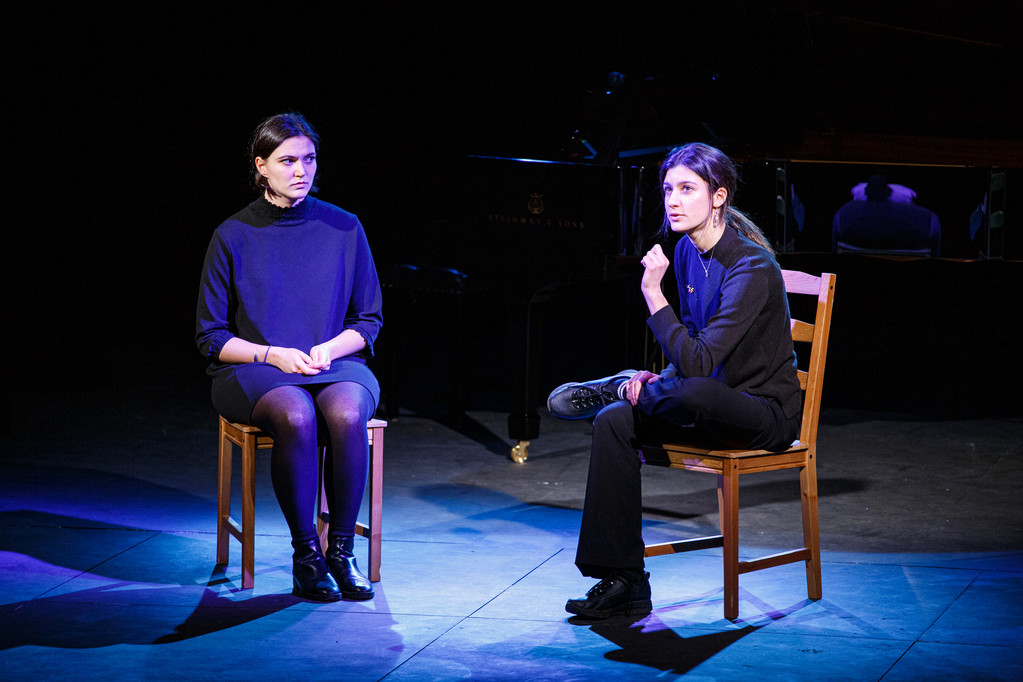 Two speakers sitting on chairs on stage