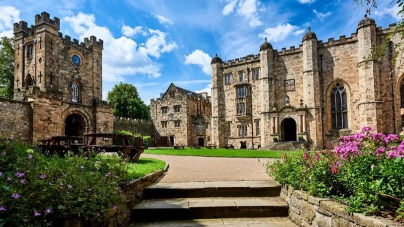 Durham Castle in the sunshine - a grass-covered courtyard surrounded by historic buildings.