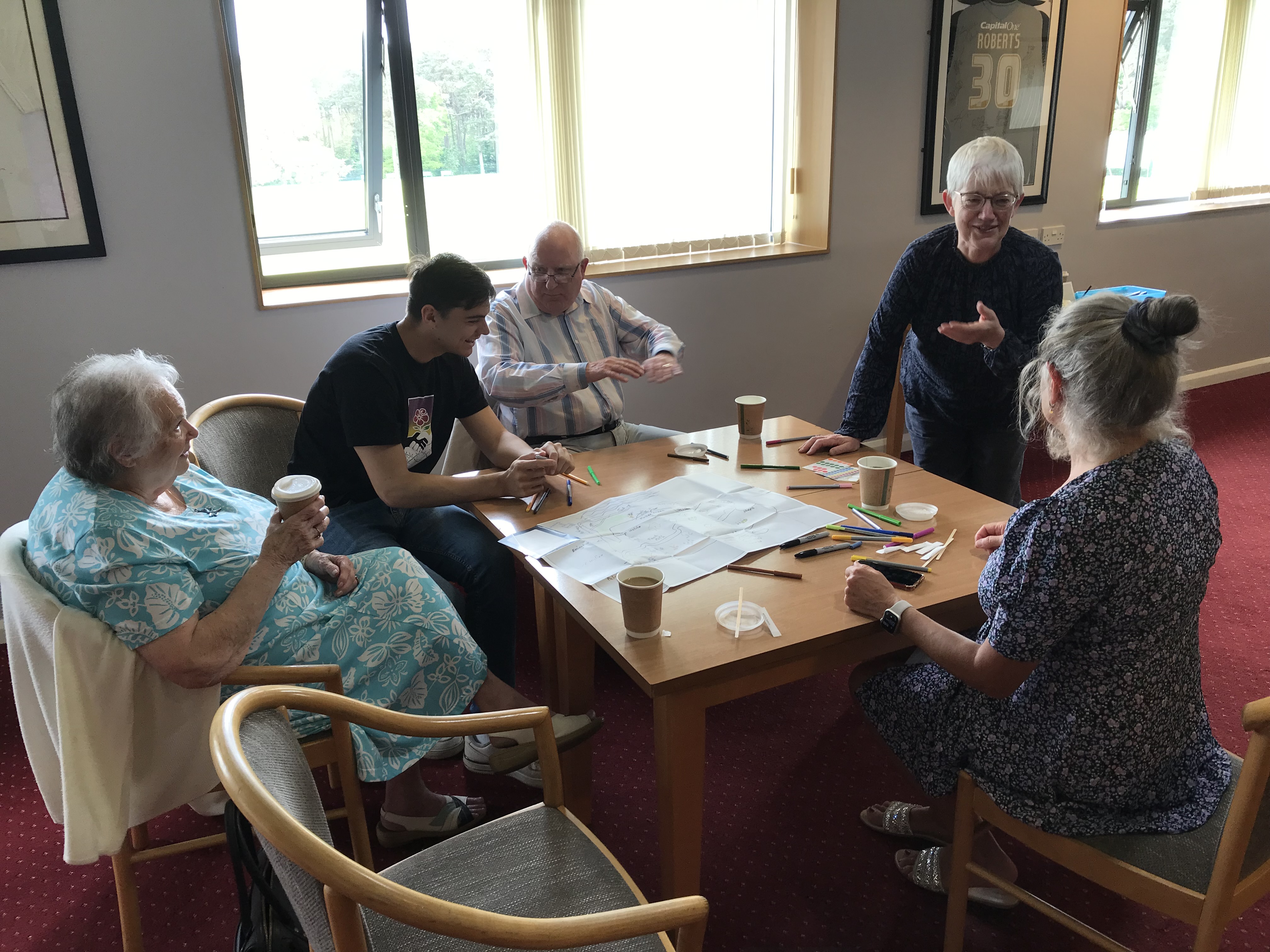 Photograph of workshop attendees sitting around a wooden table discussing the project