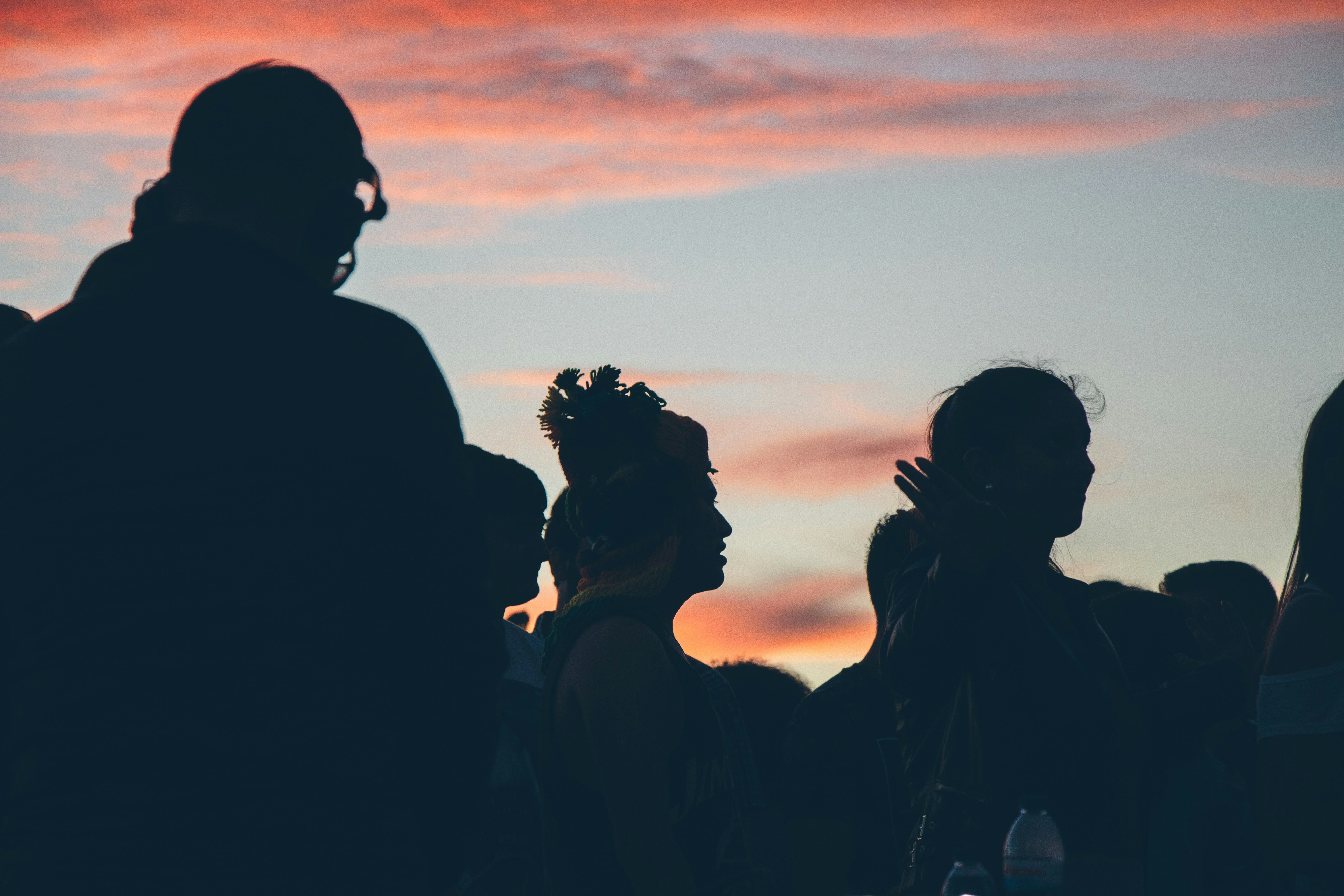 Dark silhouettes of three people against the sunset.