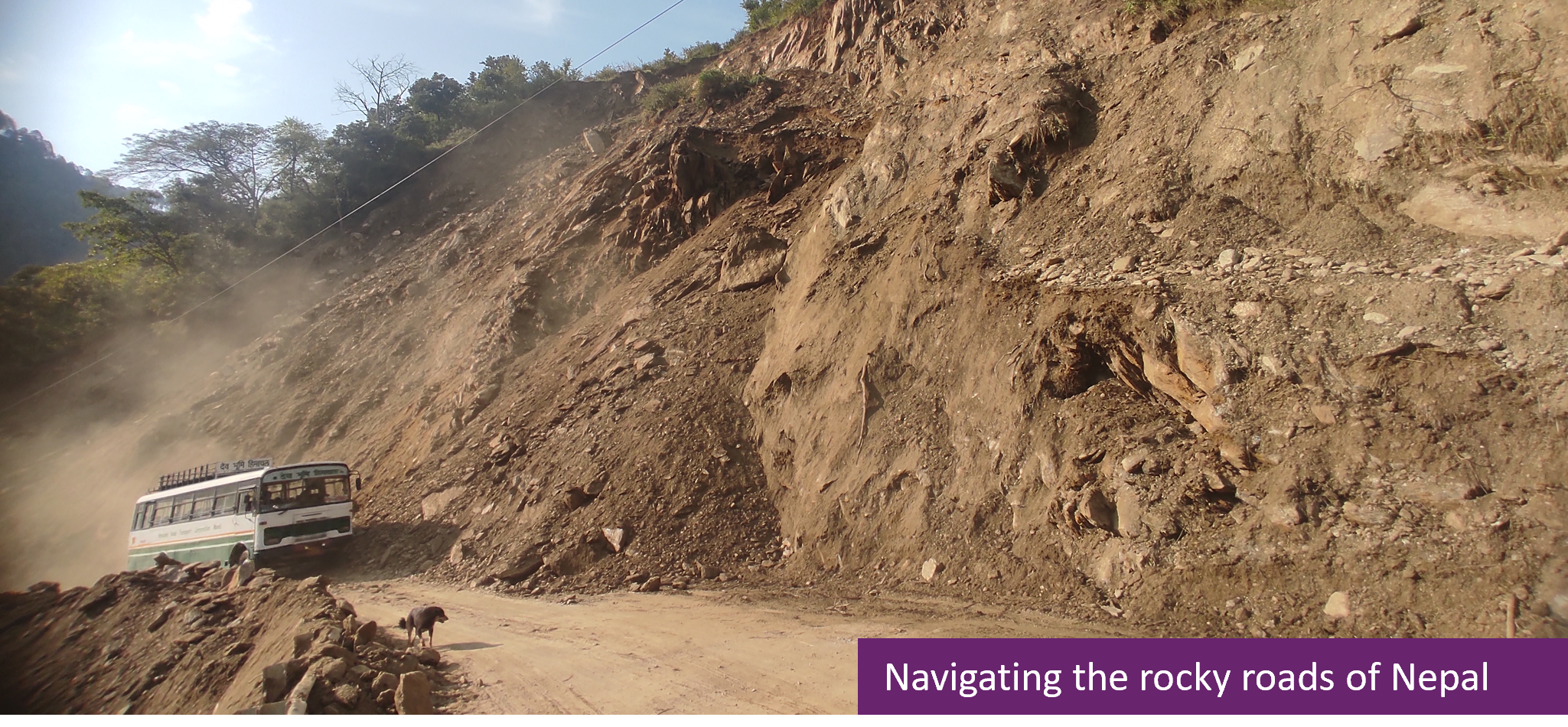 A rocky, muddy road in Nepal, with a bus driving up