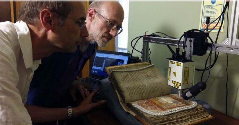 Two people examining the St Augustine Gospels at Corpus Christi College, Cambridge