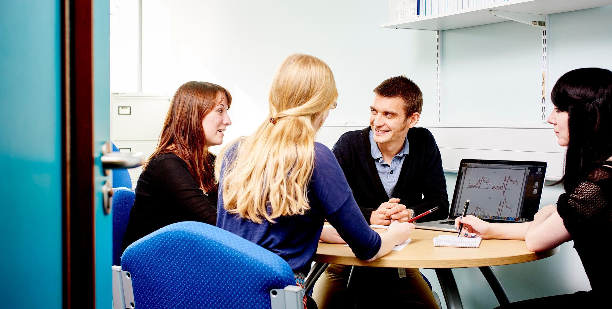 Three people looking at a computer