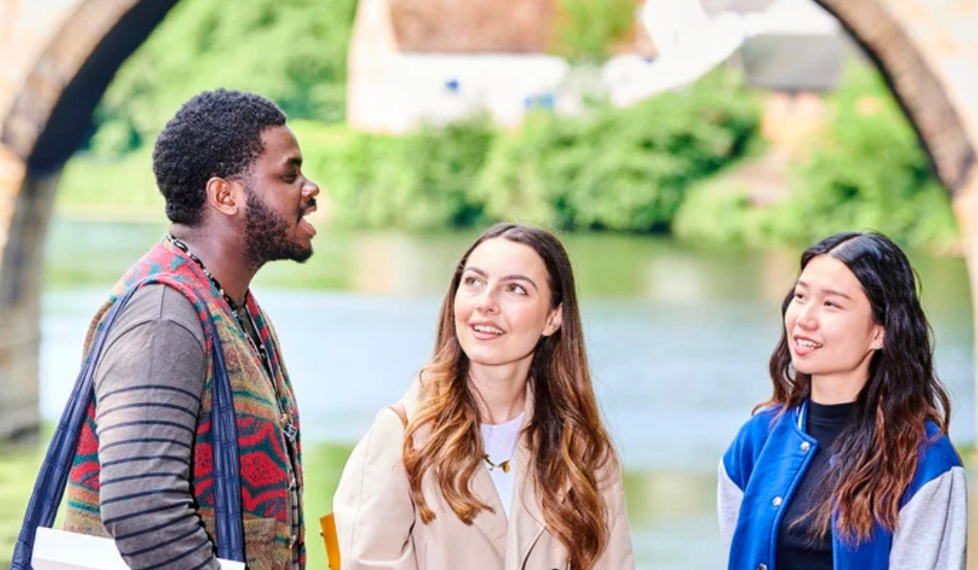Four students chatting by the Durham riverside