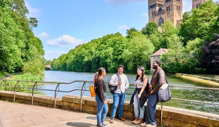 TFour students standing next to the riverside with the cathedral in the background