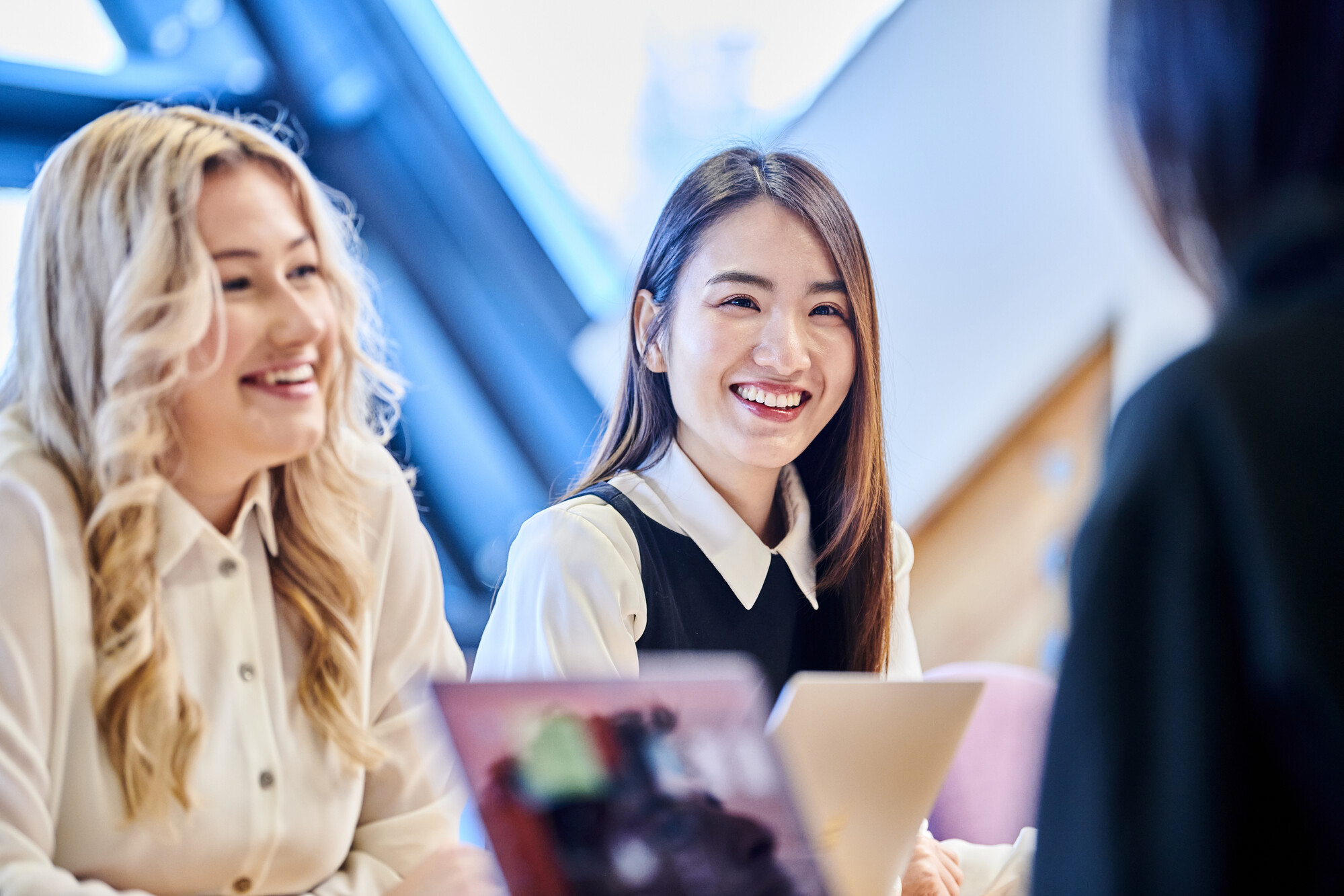 Students with laptops smiling at eachother in the Anne Galbraith Boardroom