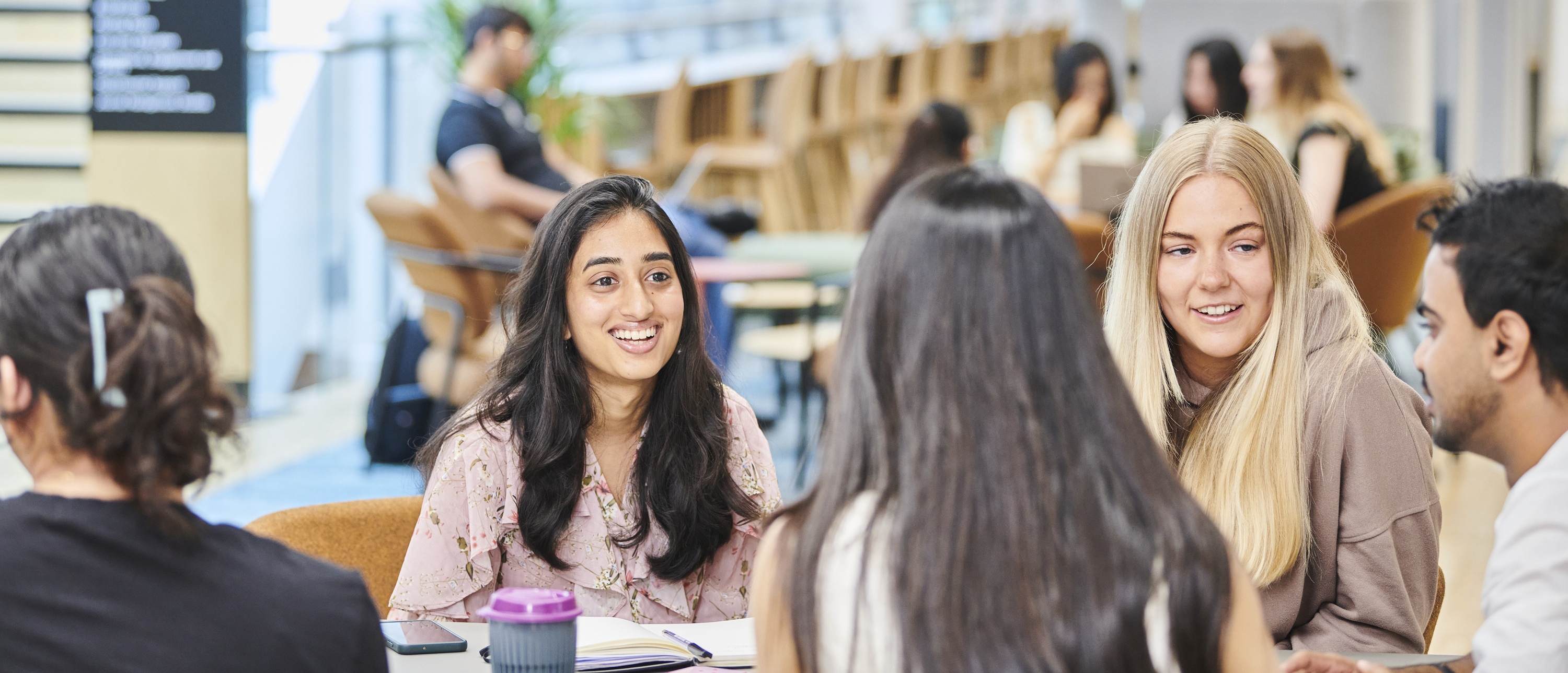 a woman standing in front of a group of people sitting at a table