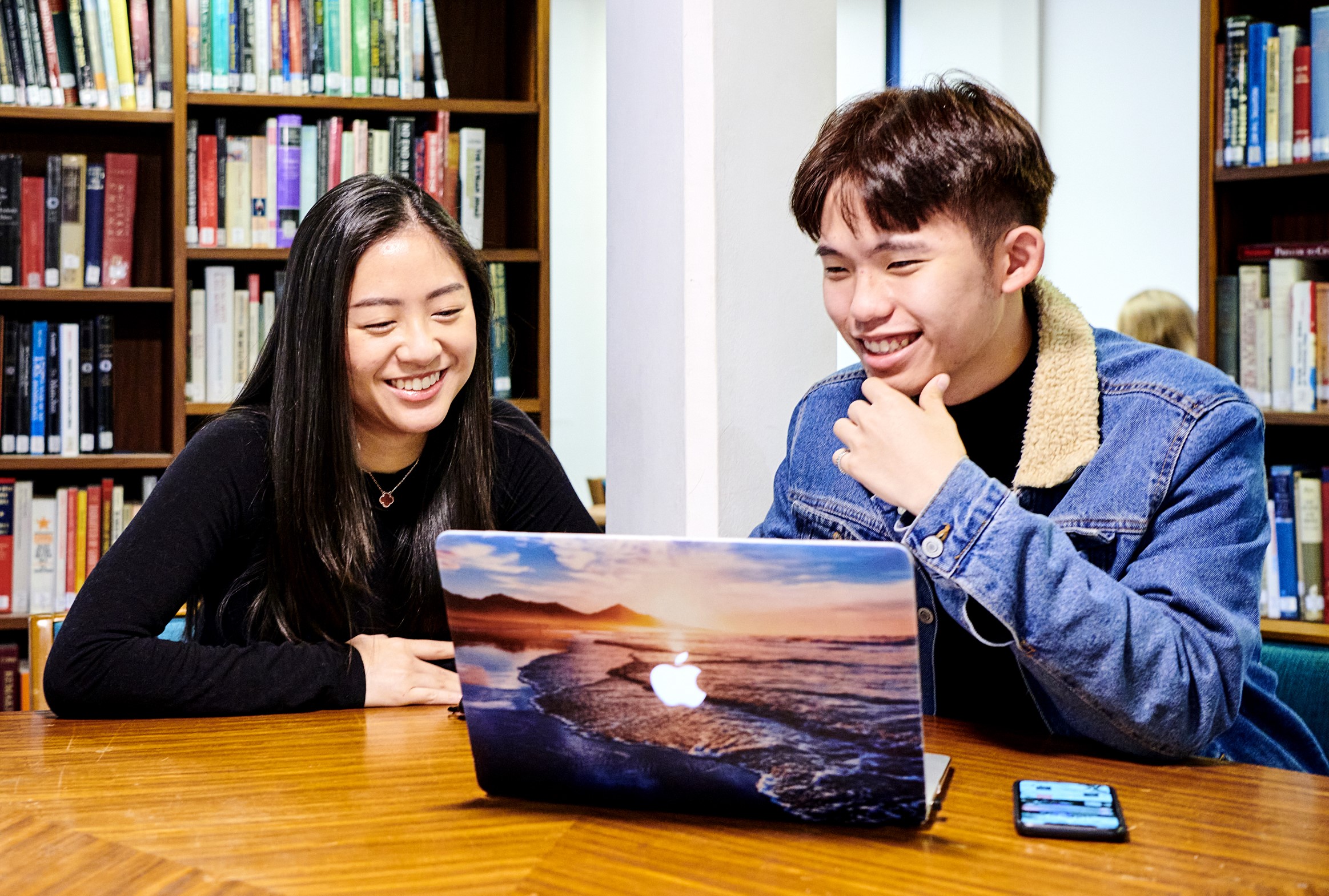 Two students with laptop in library