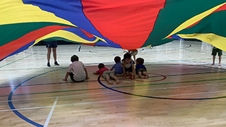 Children gathering underneath a holiday camp play parachute