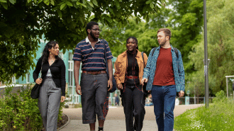 Four students walking and chatting through the campus