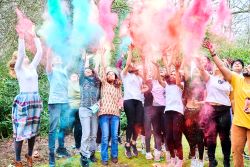 A group of students throwing coloured powder into he air, celebrating the traditional Hindu festival of Holi