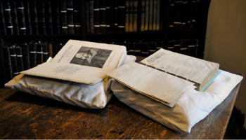 Shakespeare folios sit on book rests on a table, with bookshelves behind