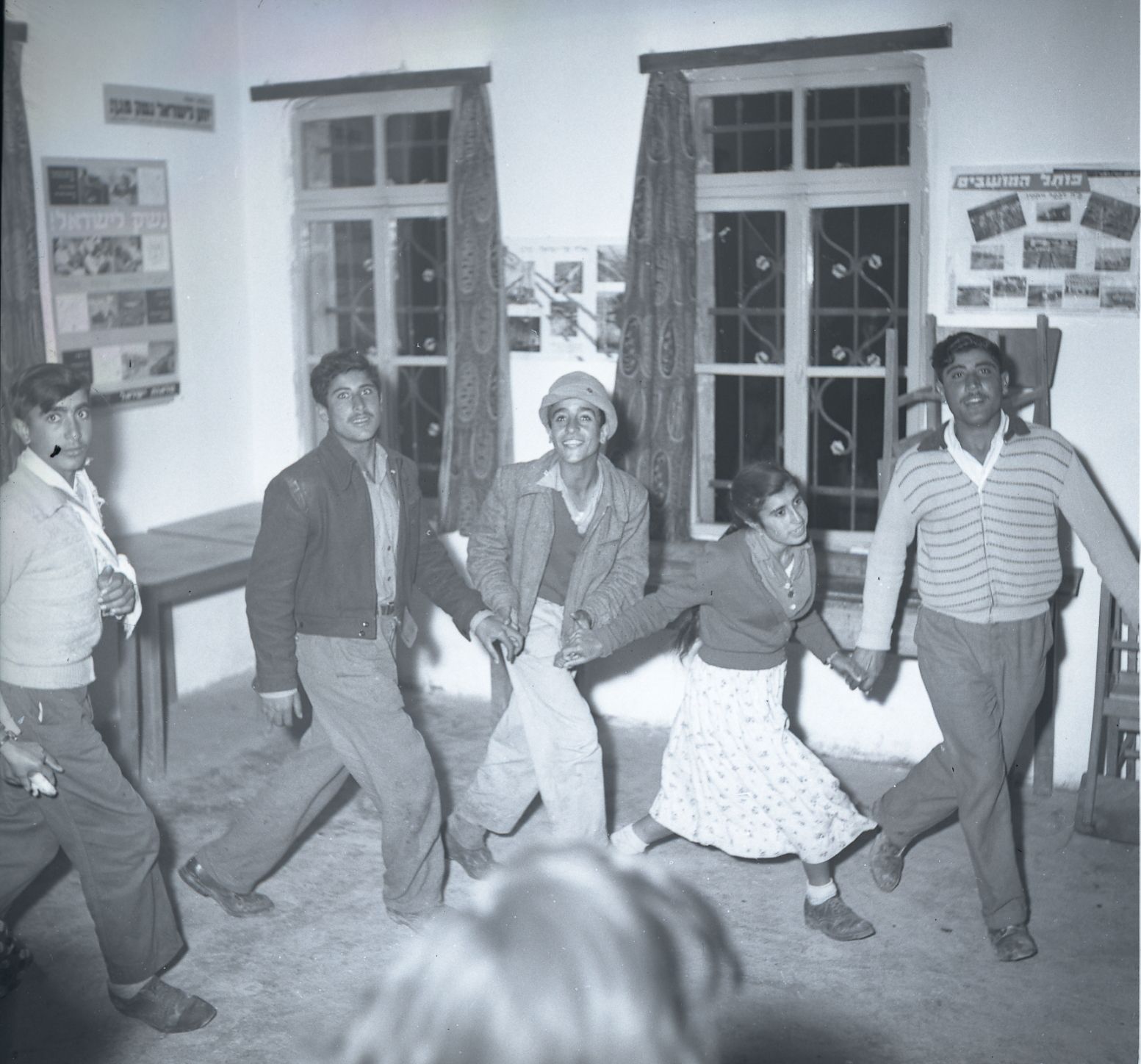 A group of people holding hands and dancing around a living room.